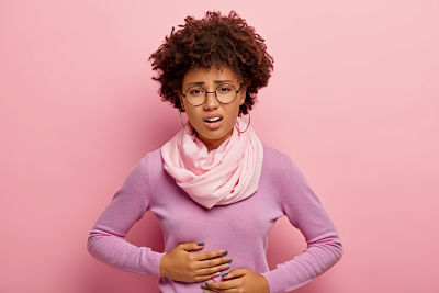 young-afro-american-woman-suffers-from-painful-cramps-in-belly-has-stomachache-frowns-face-from-pain-wears-round-spectacles-purple-jumper-with-scarf-and-earrings-being-hungr 400X267